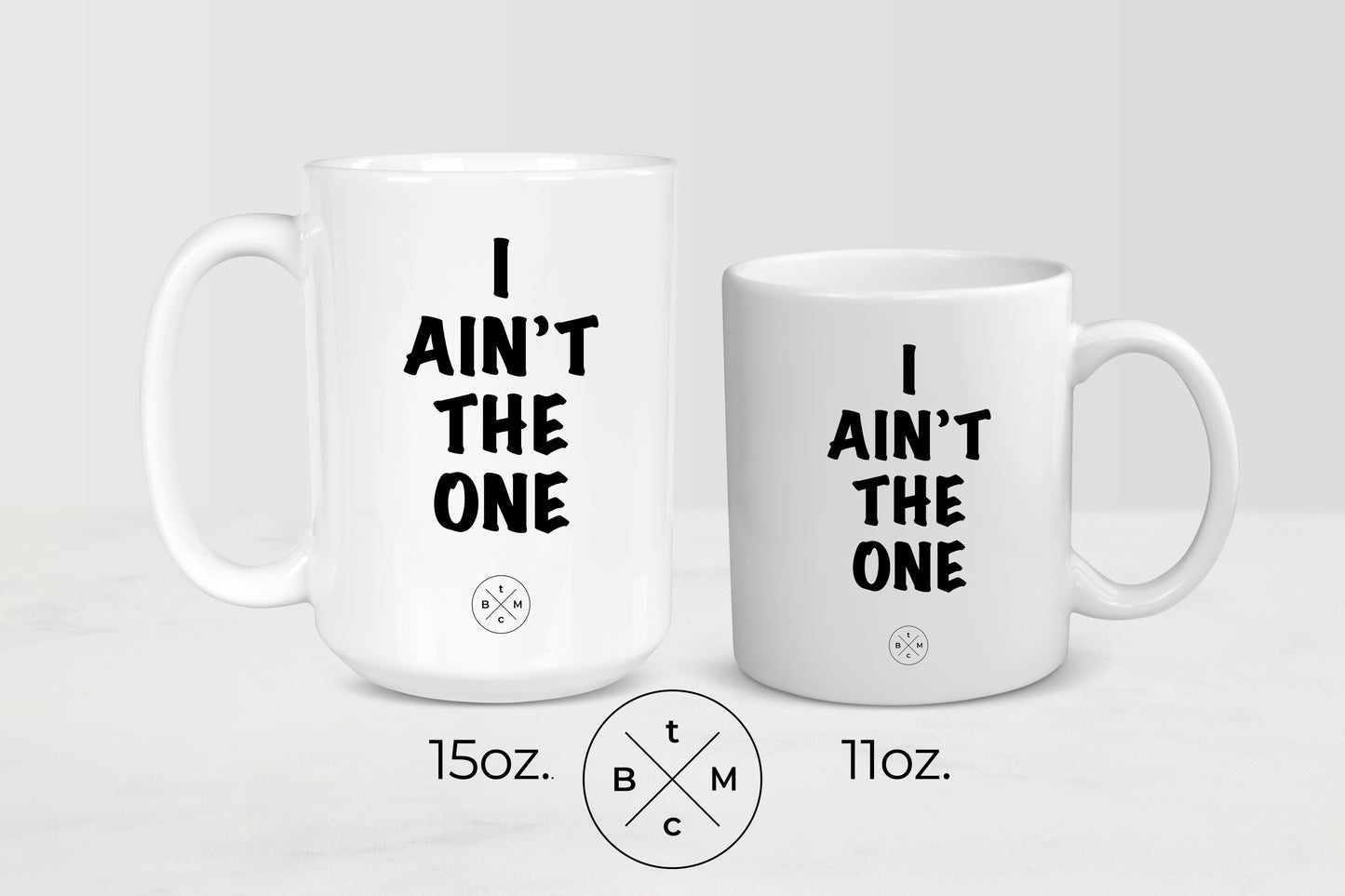 11 ounce and 15 ounce white ceramic mugs with black text I ain’t the one