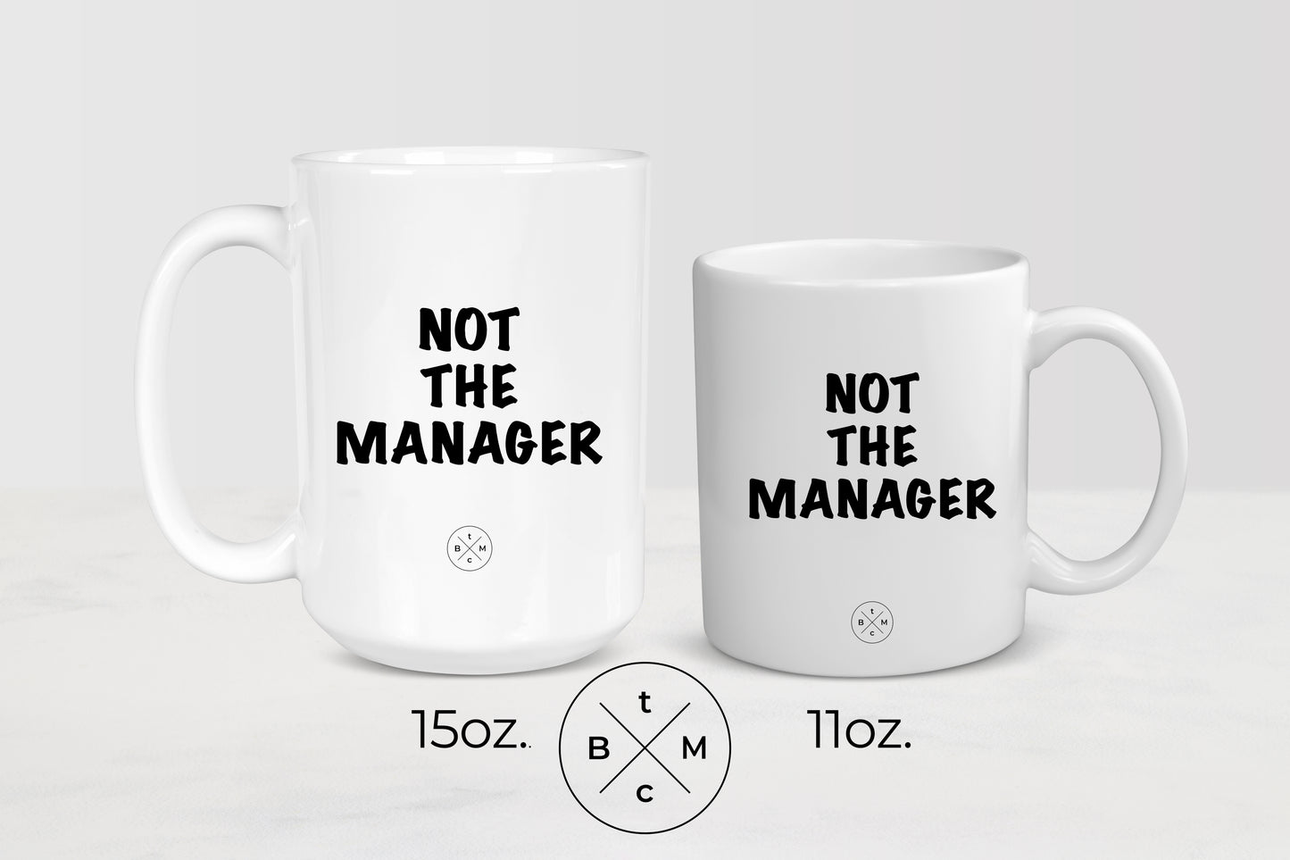 11 ounce and 15 ounce white ceramic mugs with black text not the manager
