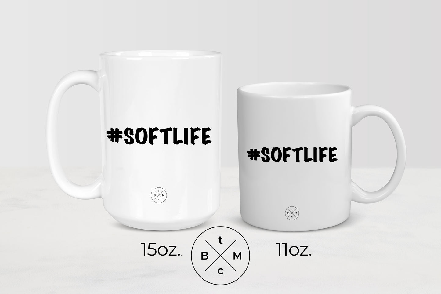 White 11 ounce and 15 ounce ceramic mugs with black text #SoftLife