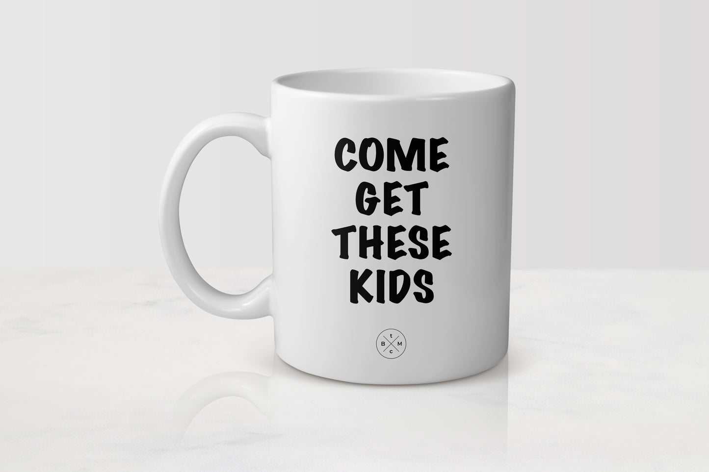 White ceramic mug with black text him get these kids