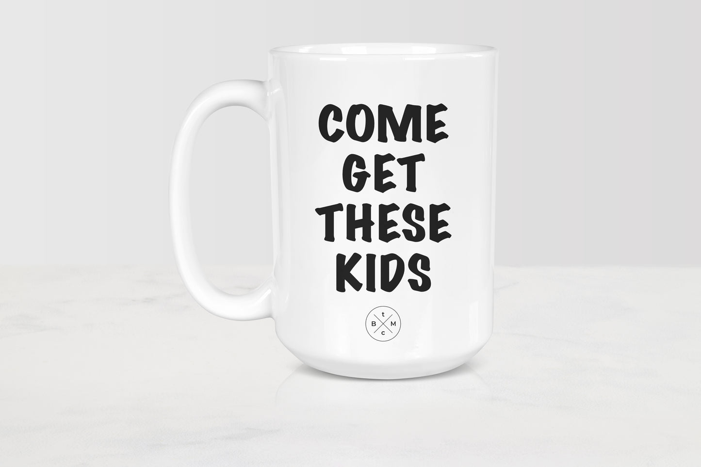 White ceramic mug with black text him get these kids