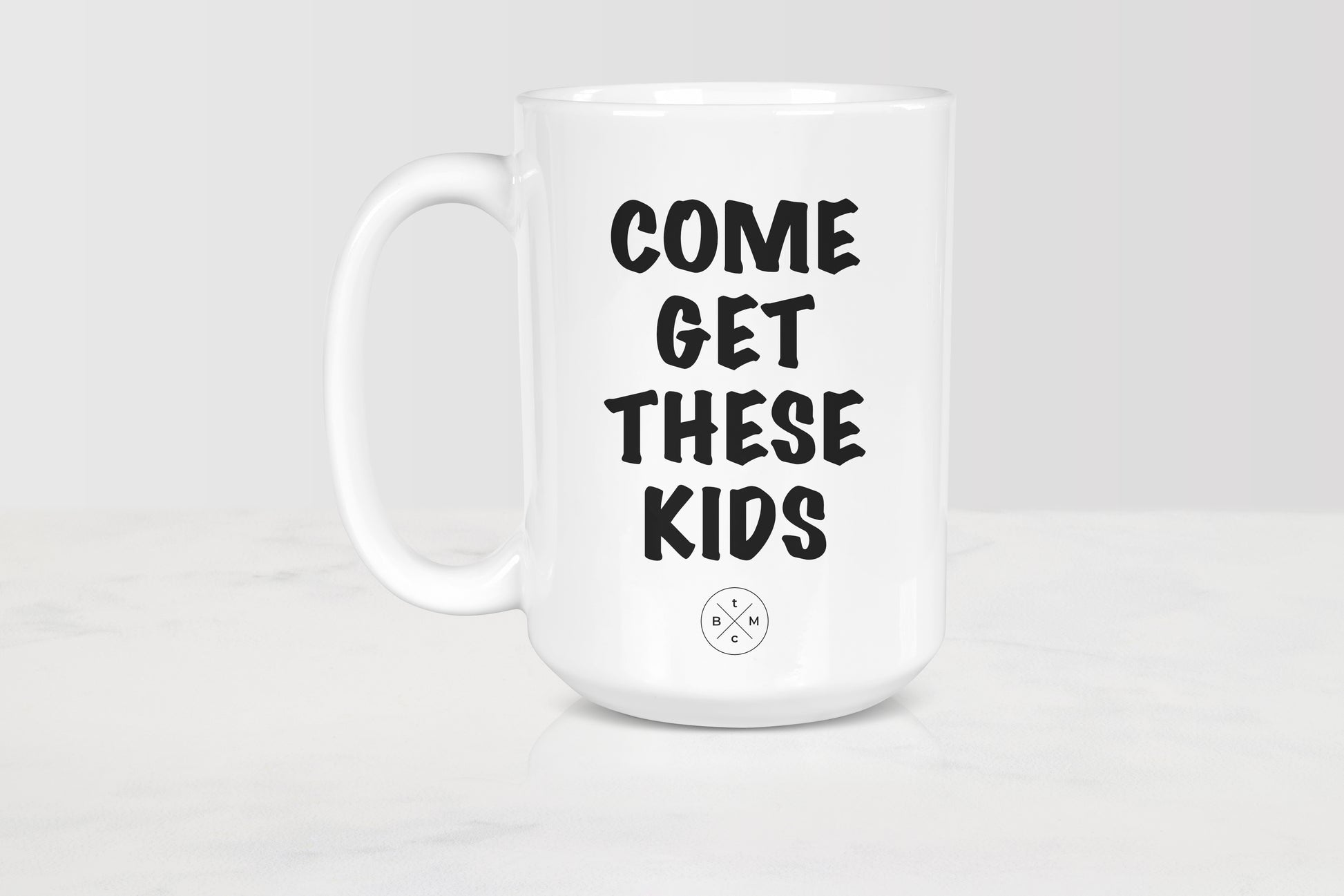 White ceramic mug with black text him get these kids