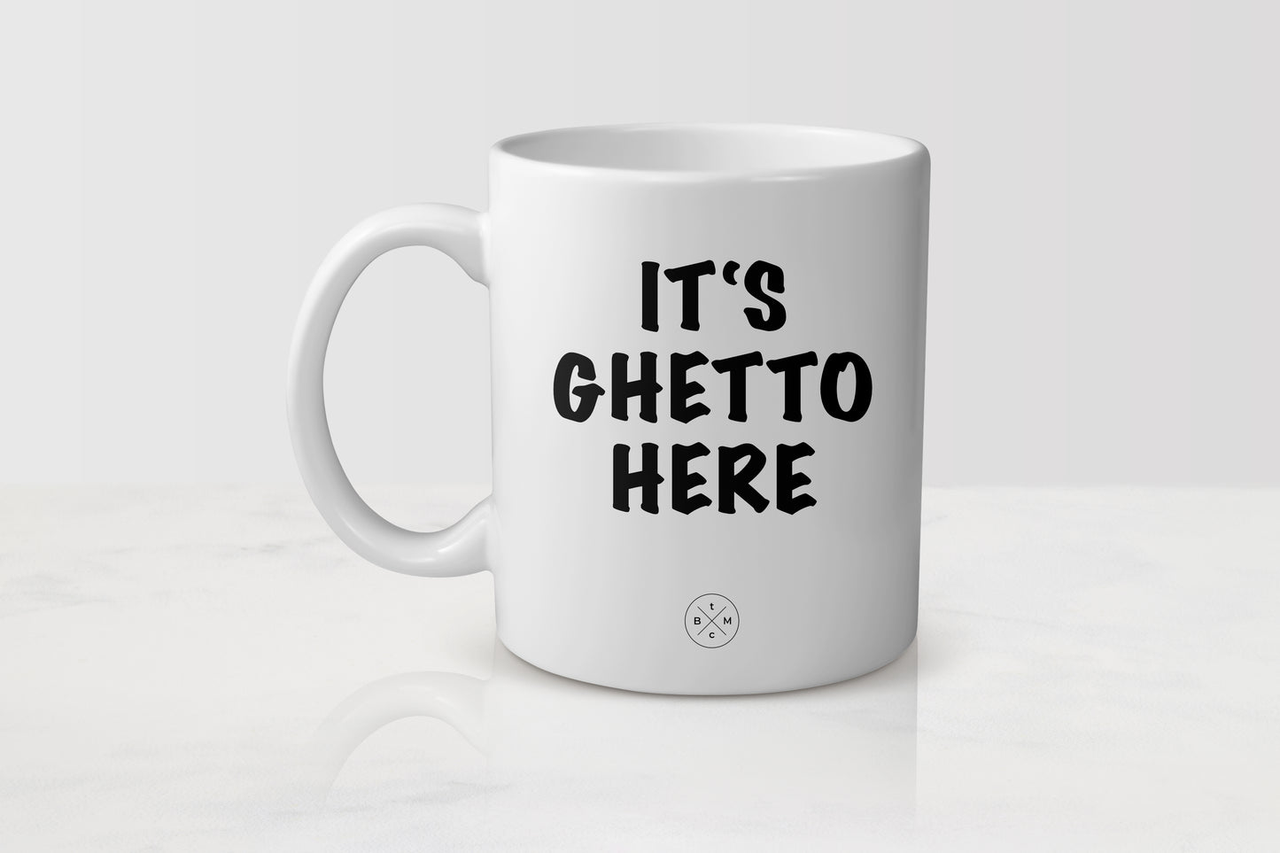 White 11 ounce ceramic mug with black text it’s ghetto here 