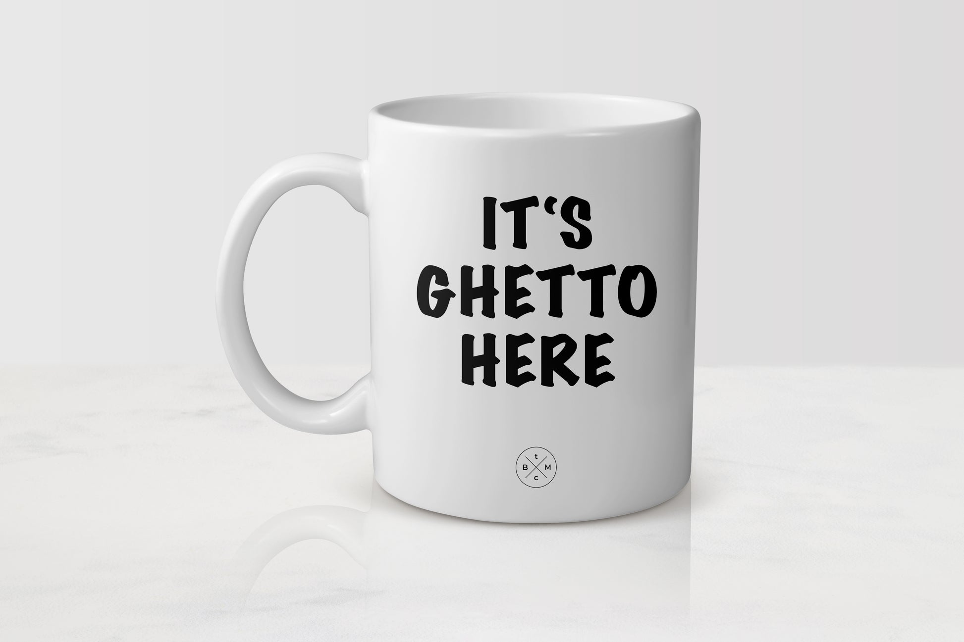 White 11 ounce ceramic mug with black text it’s ghetto here 