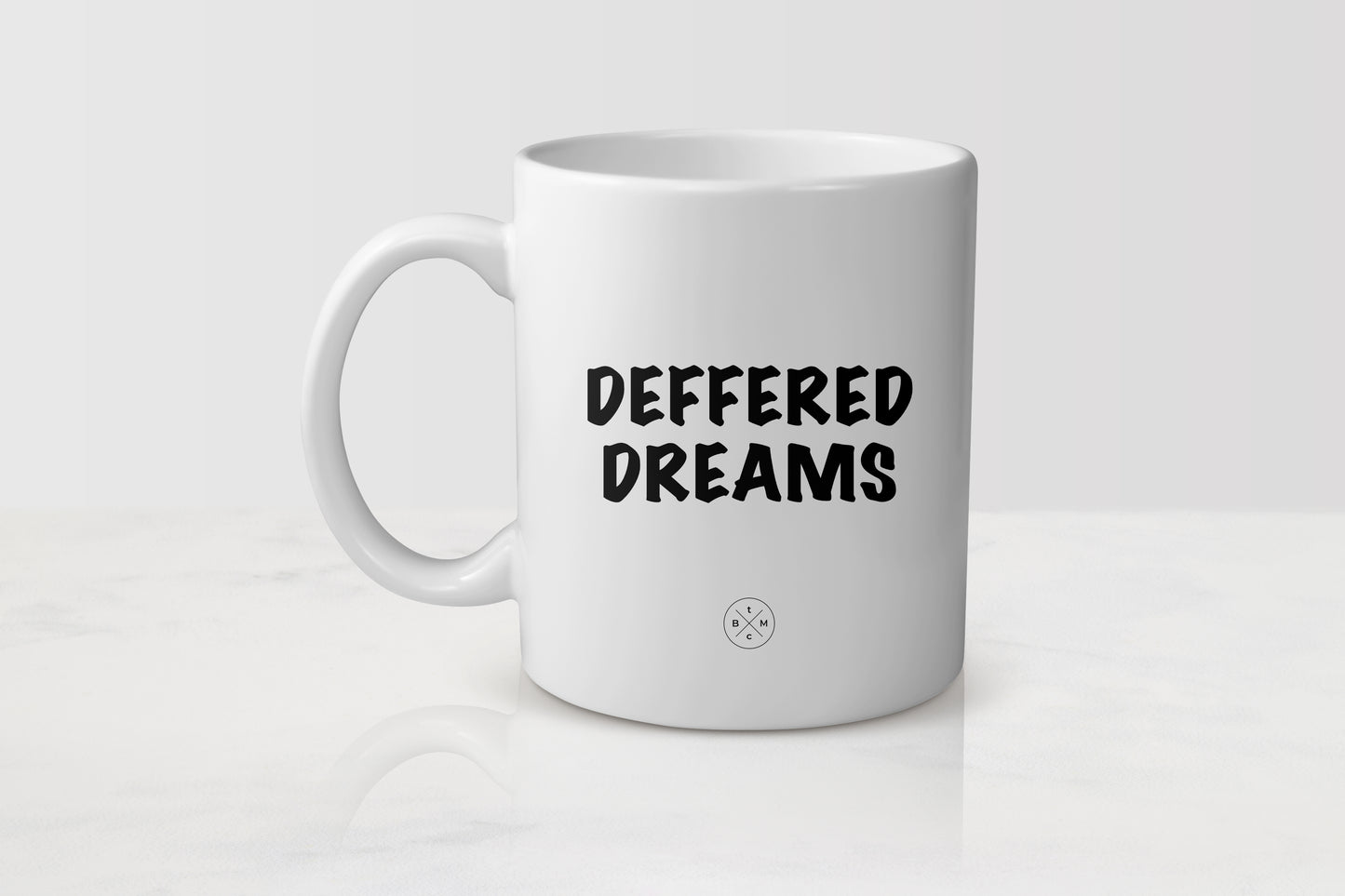 11 ounce white ceramic mug with black text deferred dreams