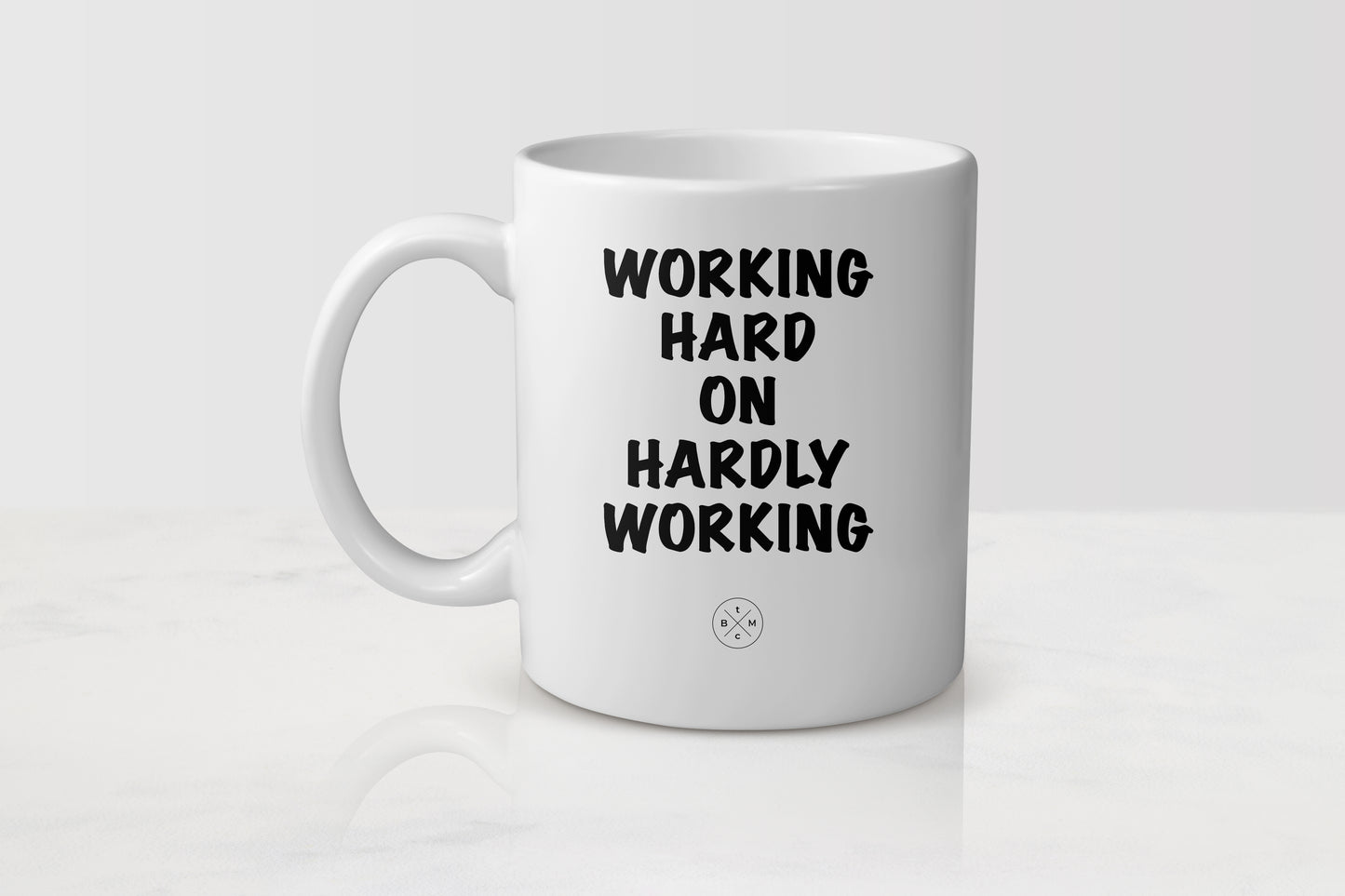 11 ounce white ceramic mug with black text working hard on hardly working