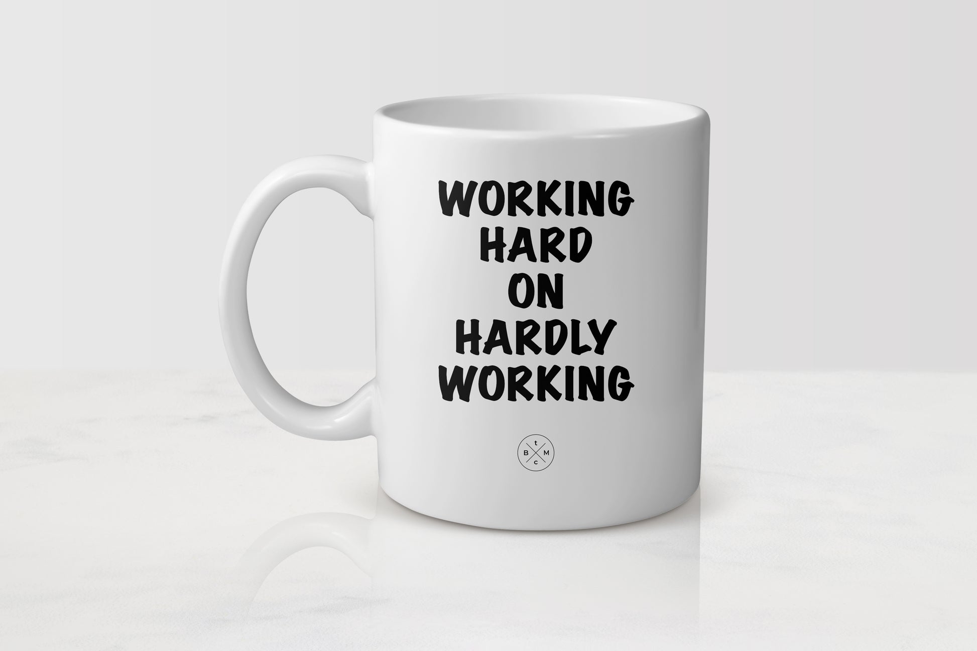 11 ounce white ceramic mug with black text working hard on hardly working