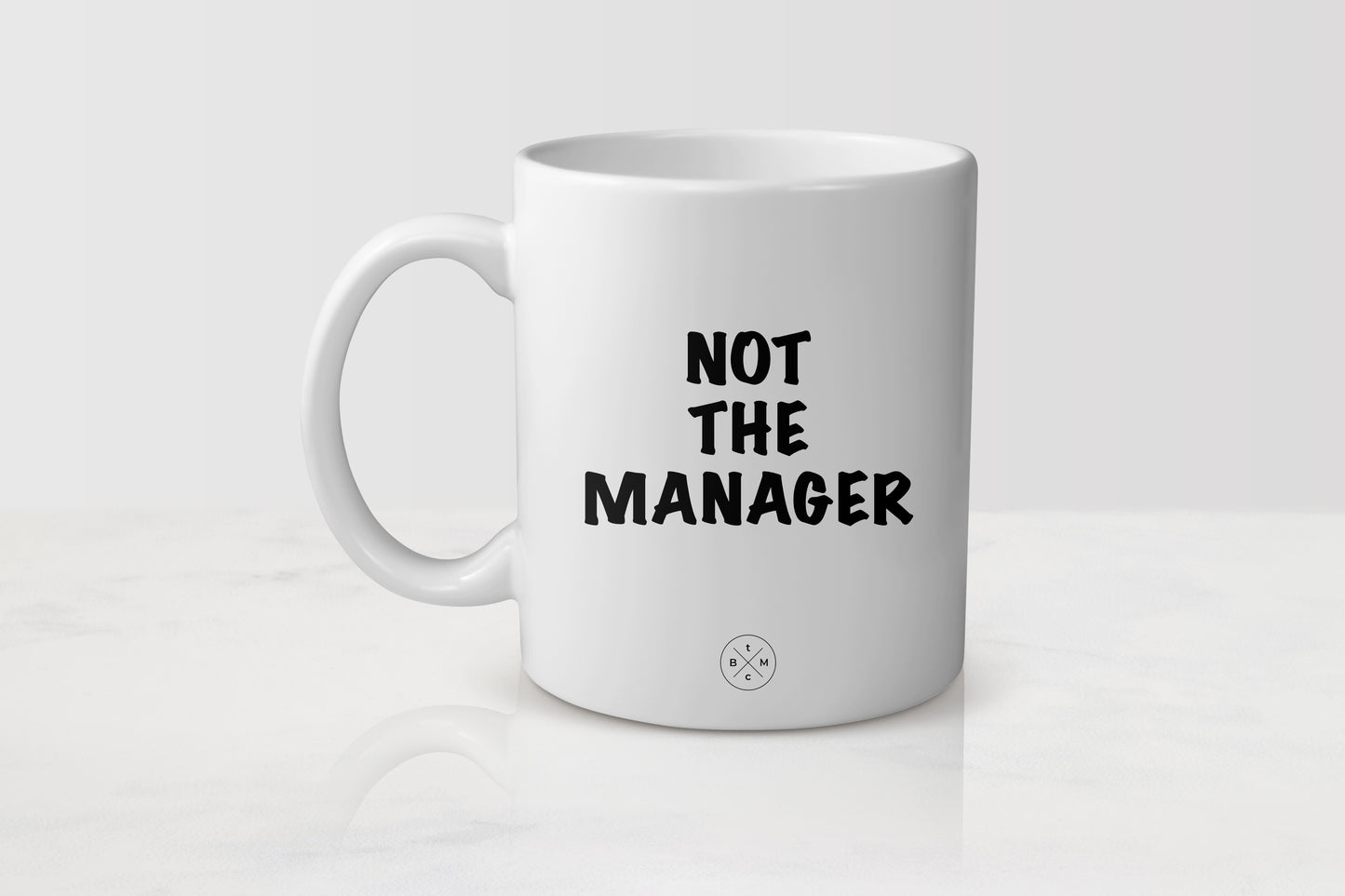 11 ounce white ceramic mug with black text not the manager