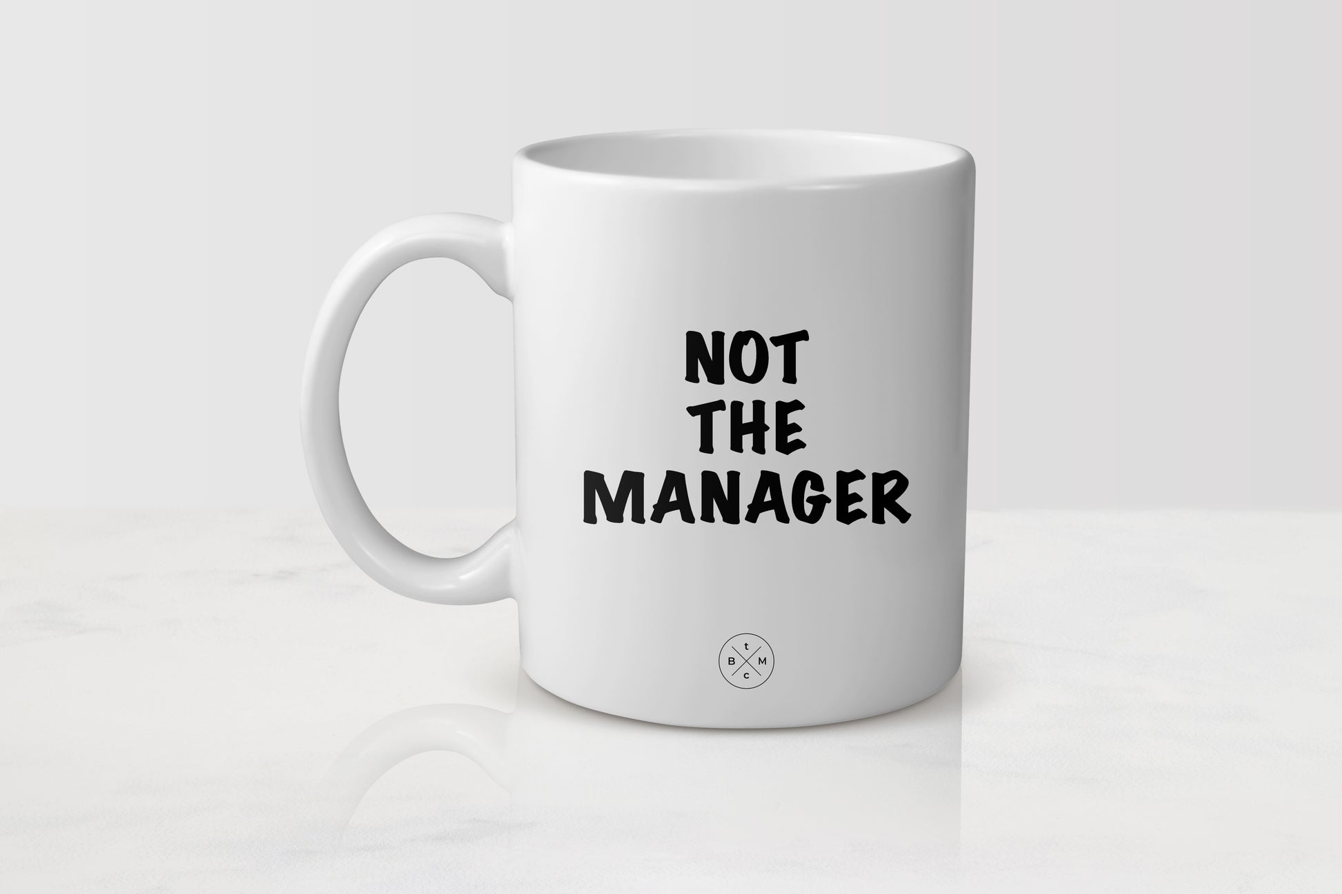 11 ounce white ceramic mug with black text not the manager