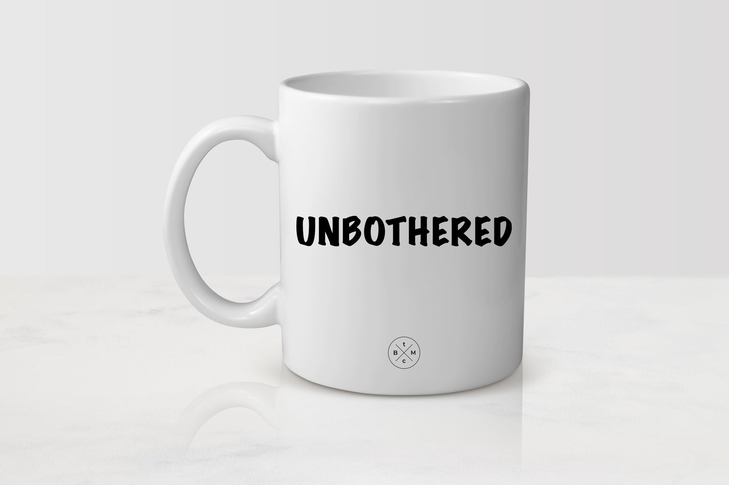 White 11 ounce ceramic mug with black text unbothered
