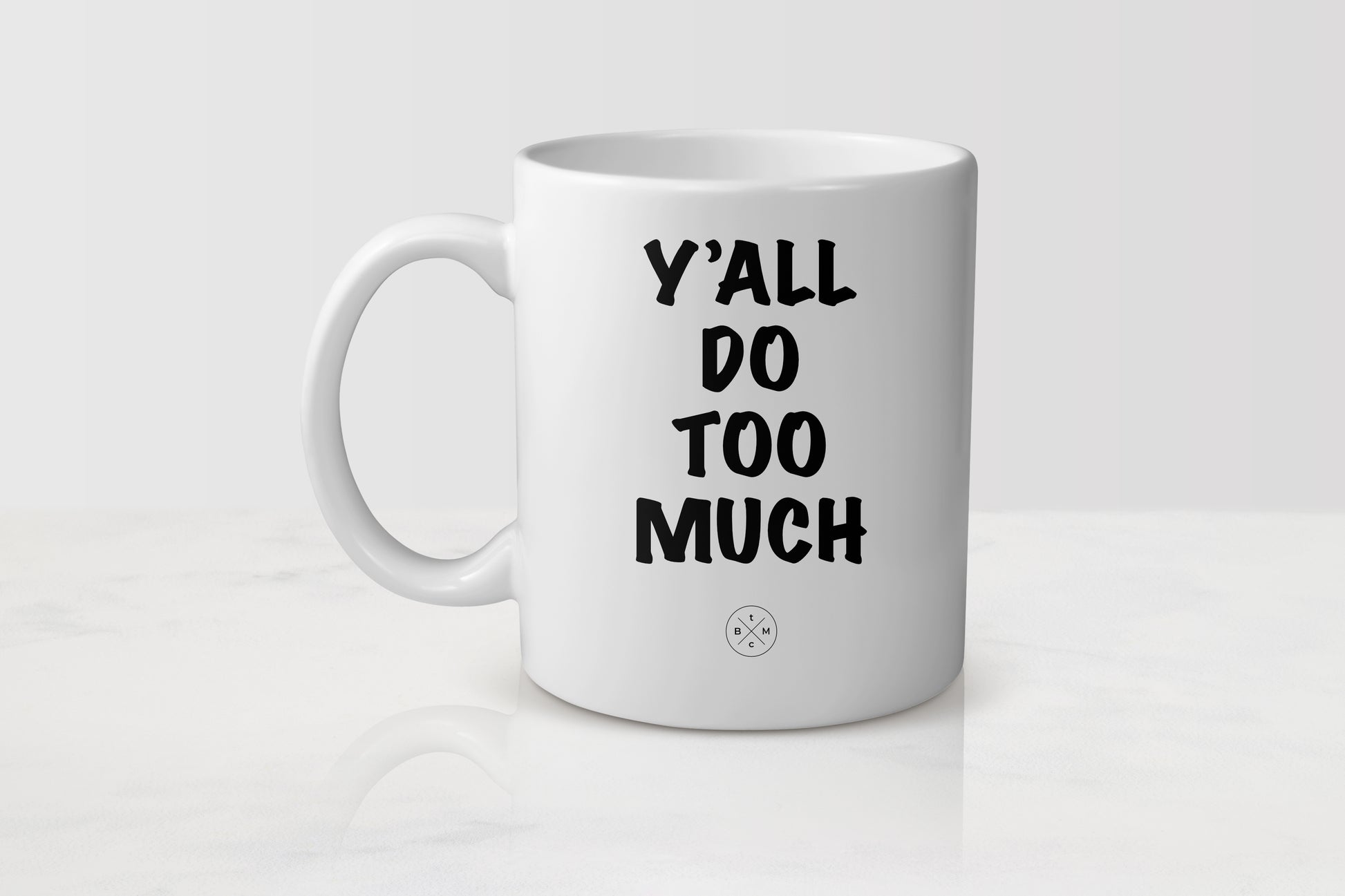 White 11 ounce ceramic mug with black text y’all do too much