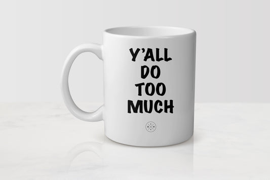 White 11 ounce ceramic mug with black text y’all do too much