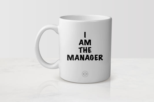 11 ounce white ceramic mug with black text I am the manager