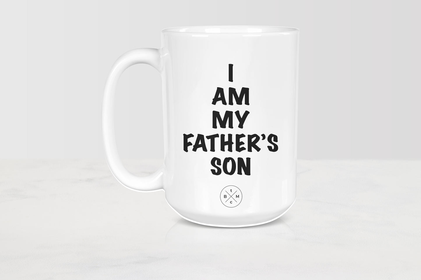 15 ounce white ceramic mug with black text I am my father’s son