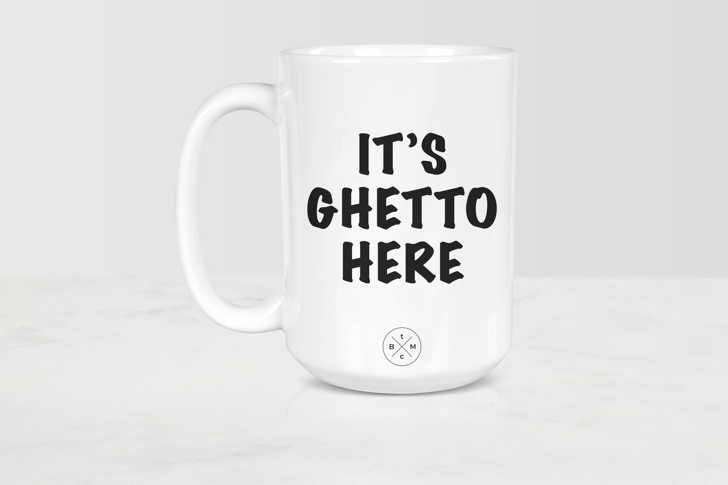 White 15 ounce ceramic mug with black text it’s ghetto here 