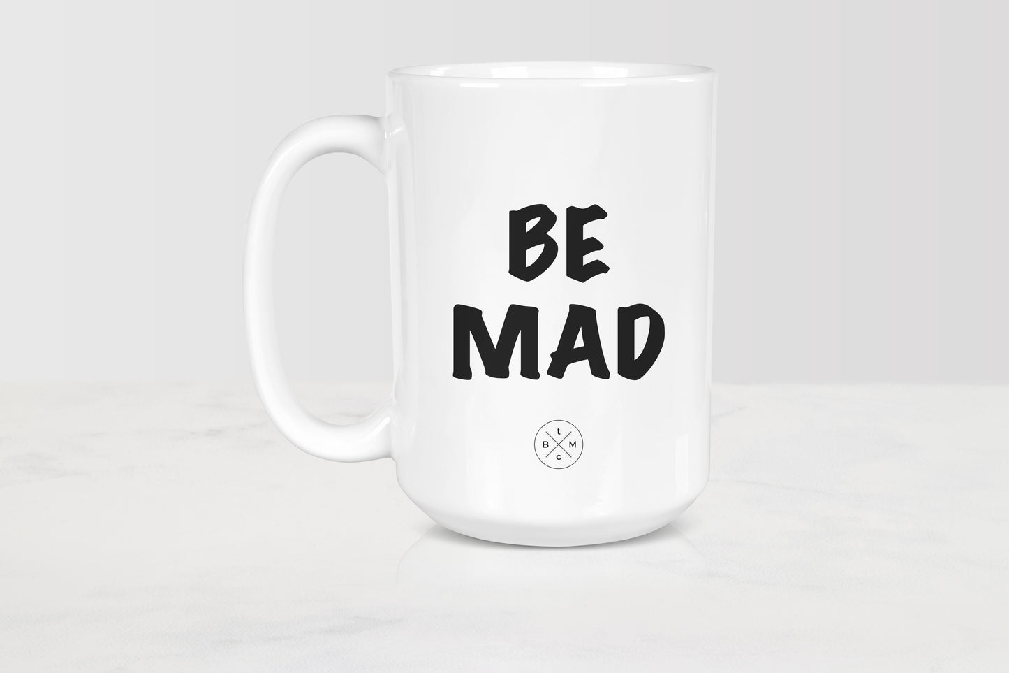White 15 ounce ceramic mug with black text be mad