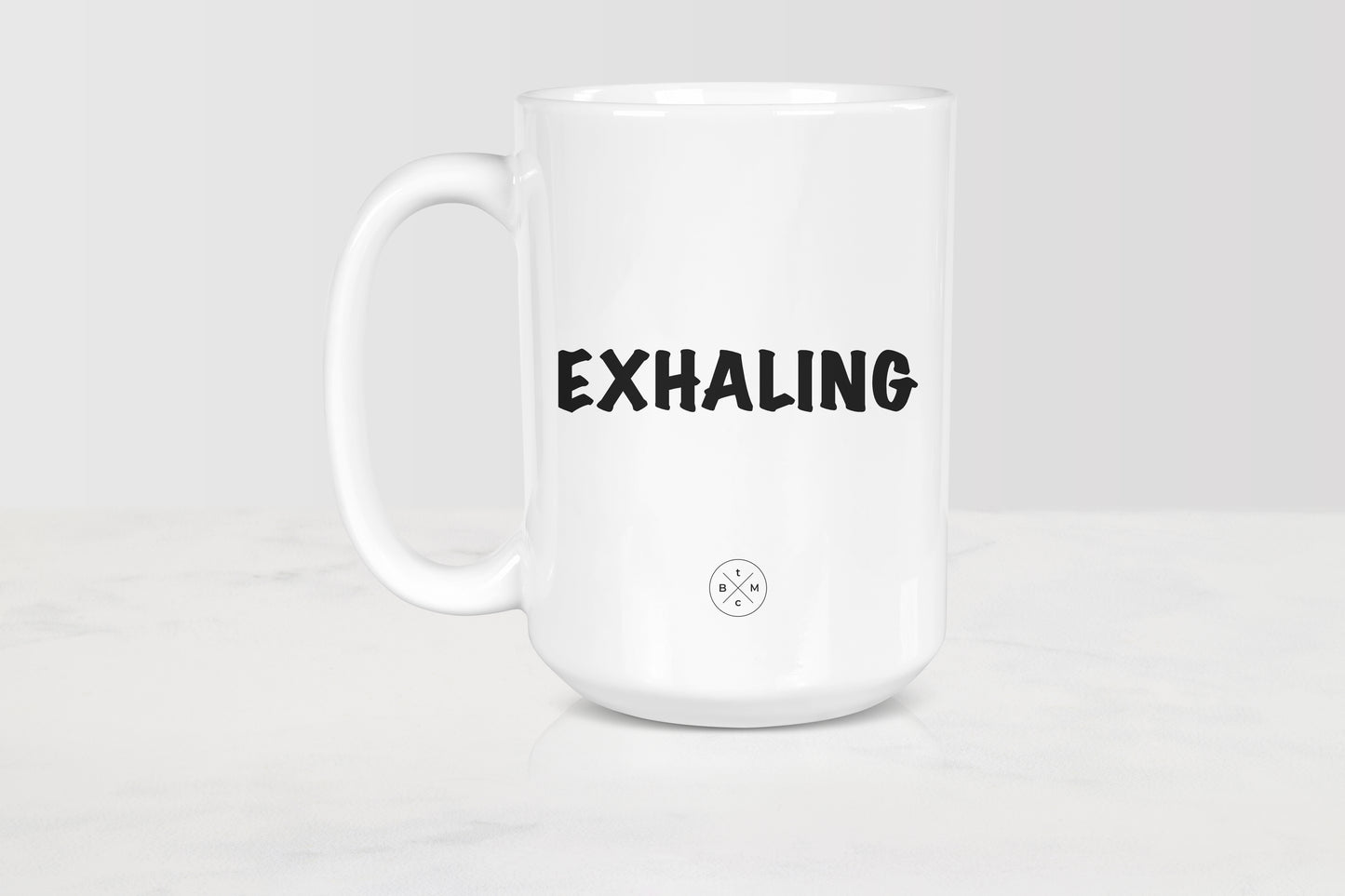 White 15 ounce ceramic mug with black text exhaling