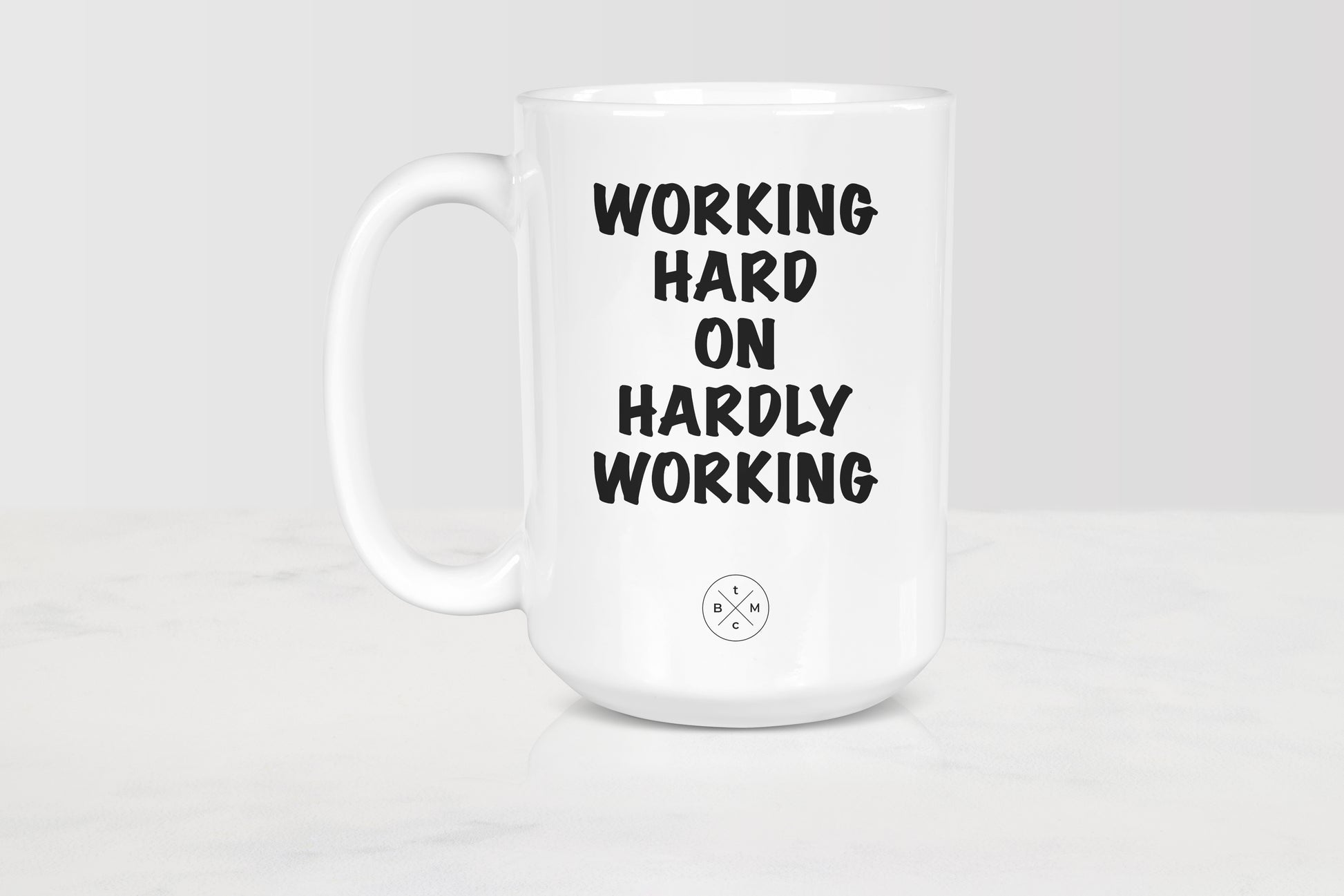 15 ounce white ceramic mug with black text working hard on hardly working