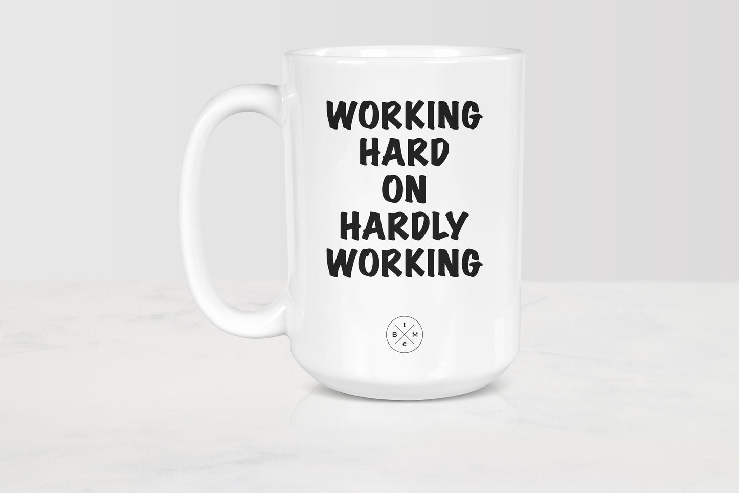 15 ounce white ceramic mug with black text working hard on hardly working