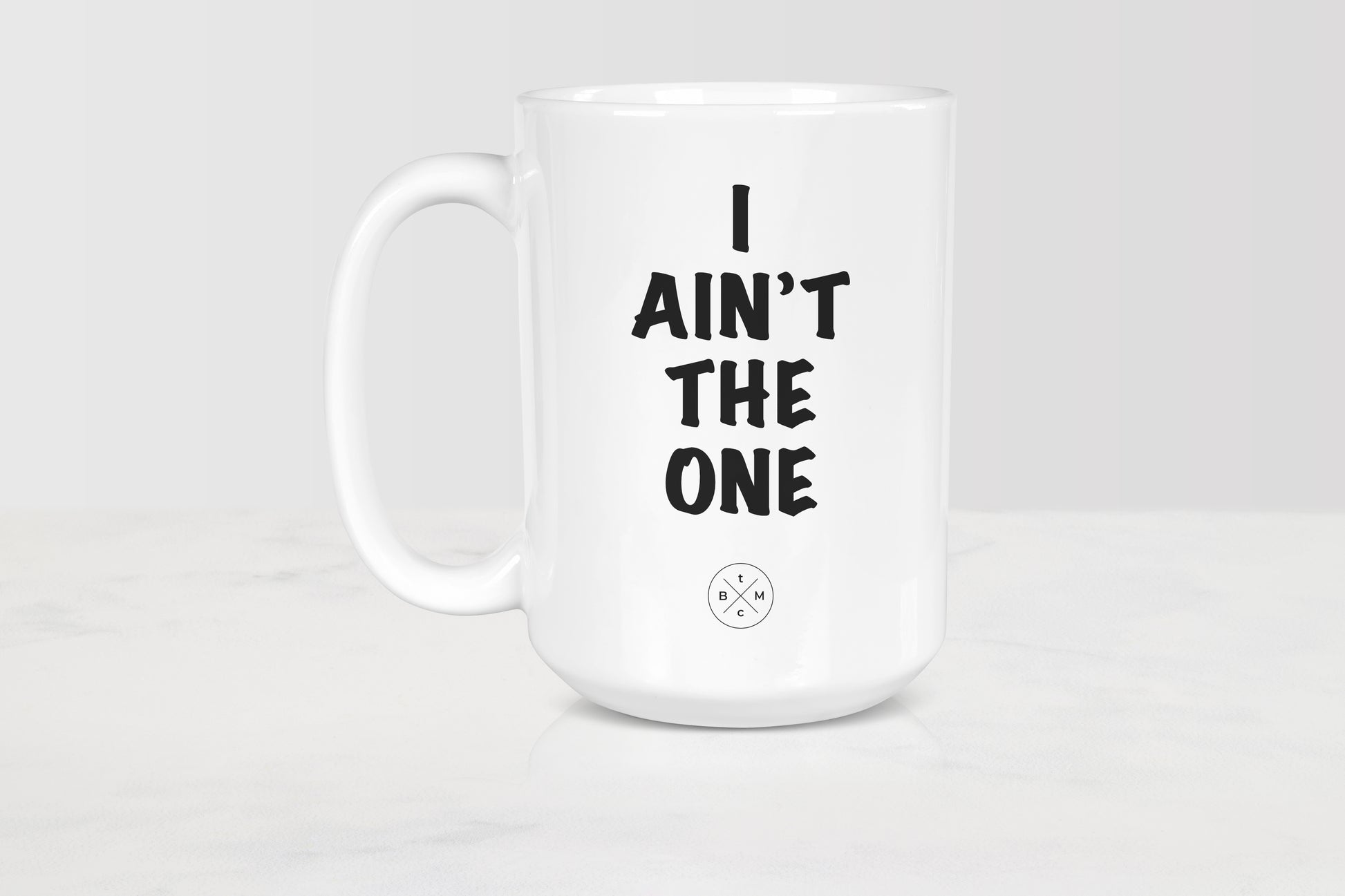 15 ounce white ceramic mug with black text I ain’t the one
