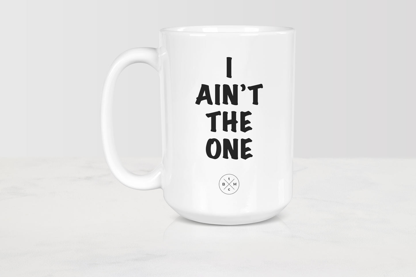 15 ounce white ceramic mug with black text I ain’t the one