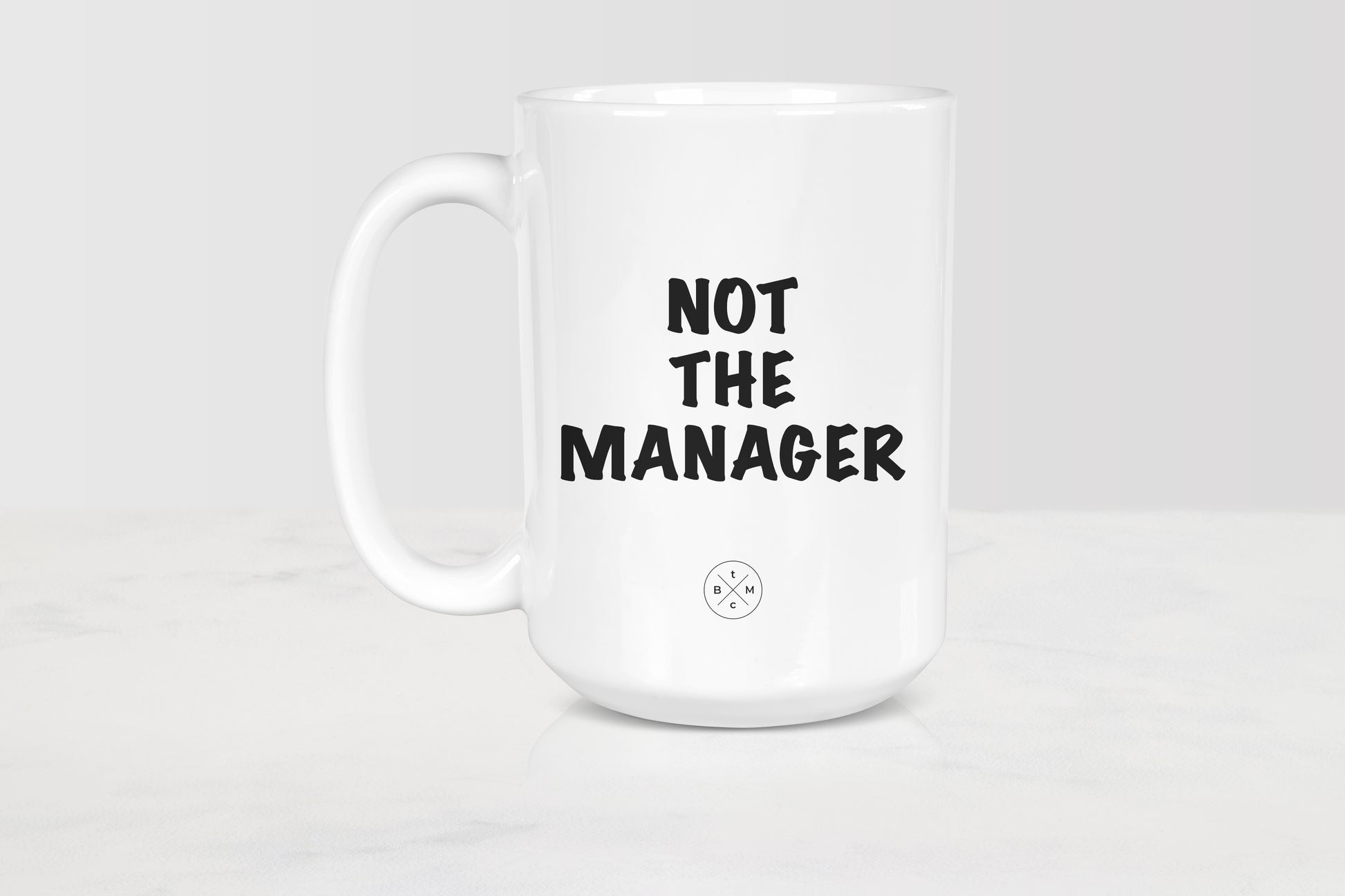 15 ounce white ceramic mug with black text not the manager