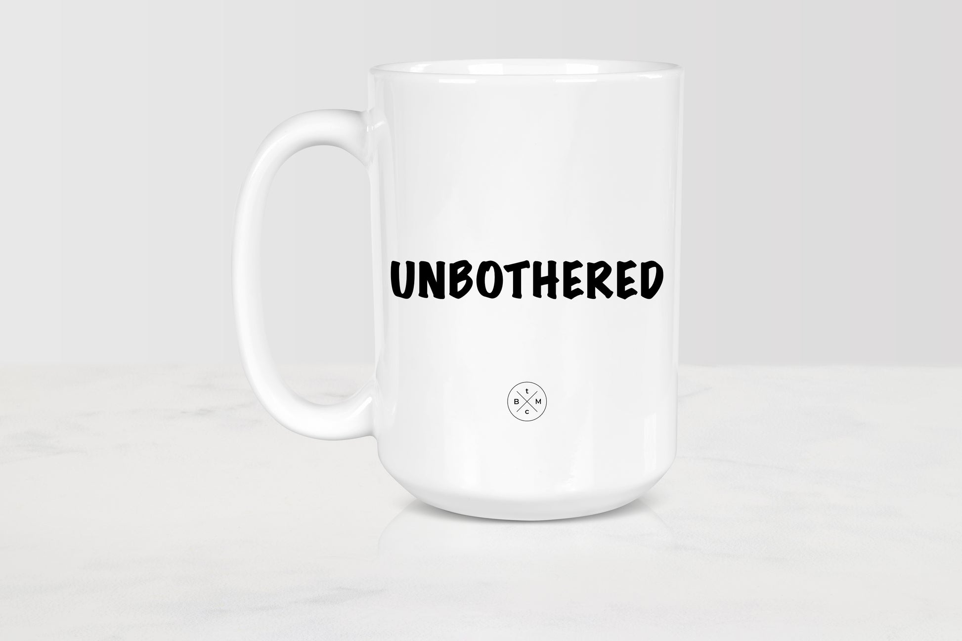 White 15 ounce ceramic mug with black text unbothered