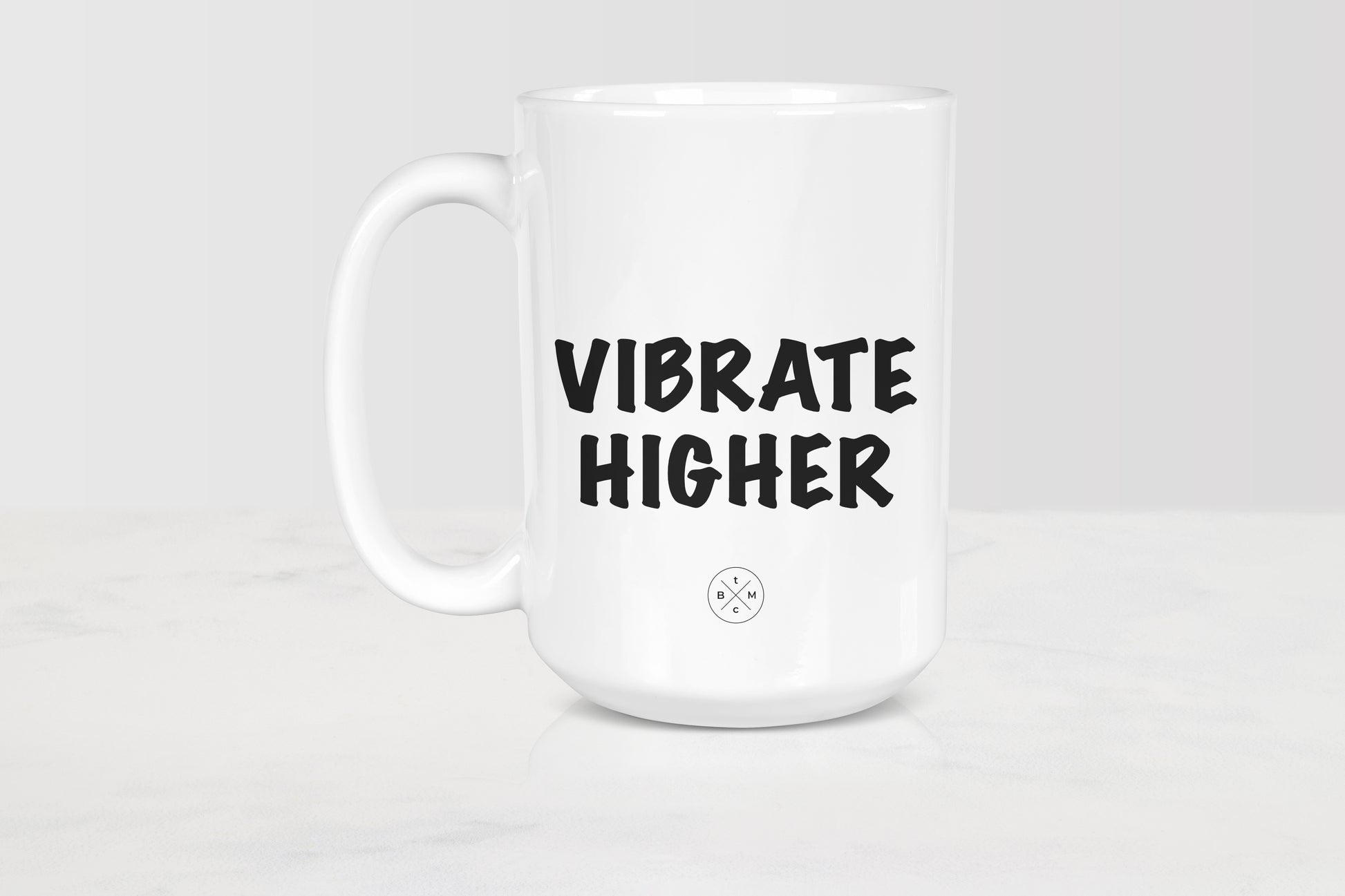 White 15 ounce ceramic mug with black text vibrate higher