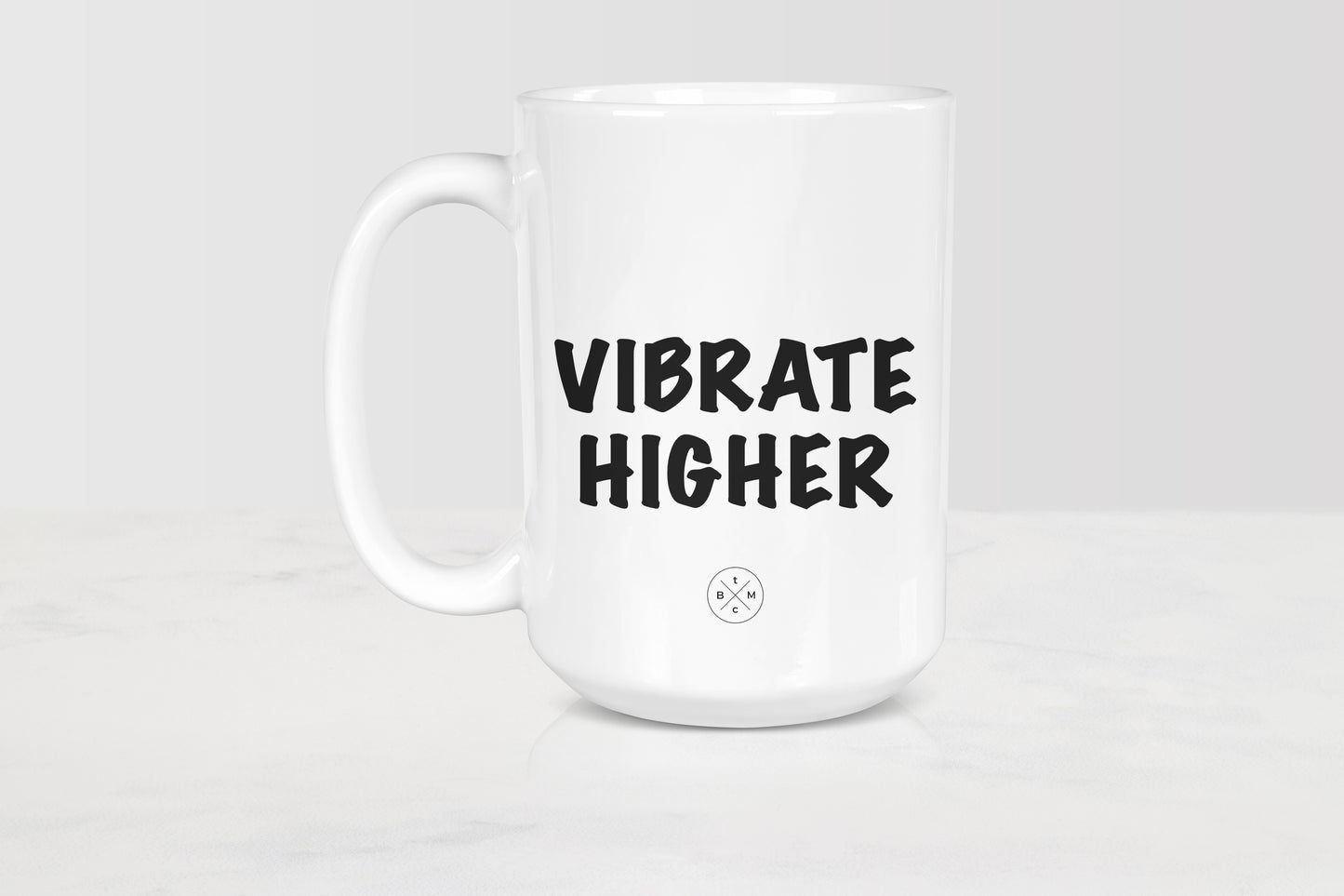 White 15 ounce ceramic mug with black text vibrate higher