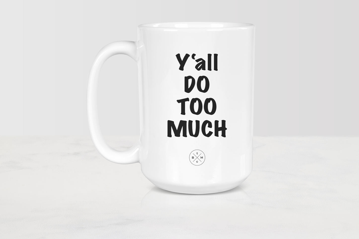 15 ounce white ceramic mug with black text y’all do too much