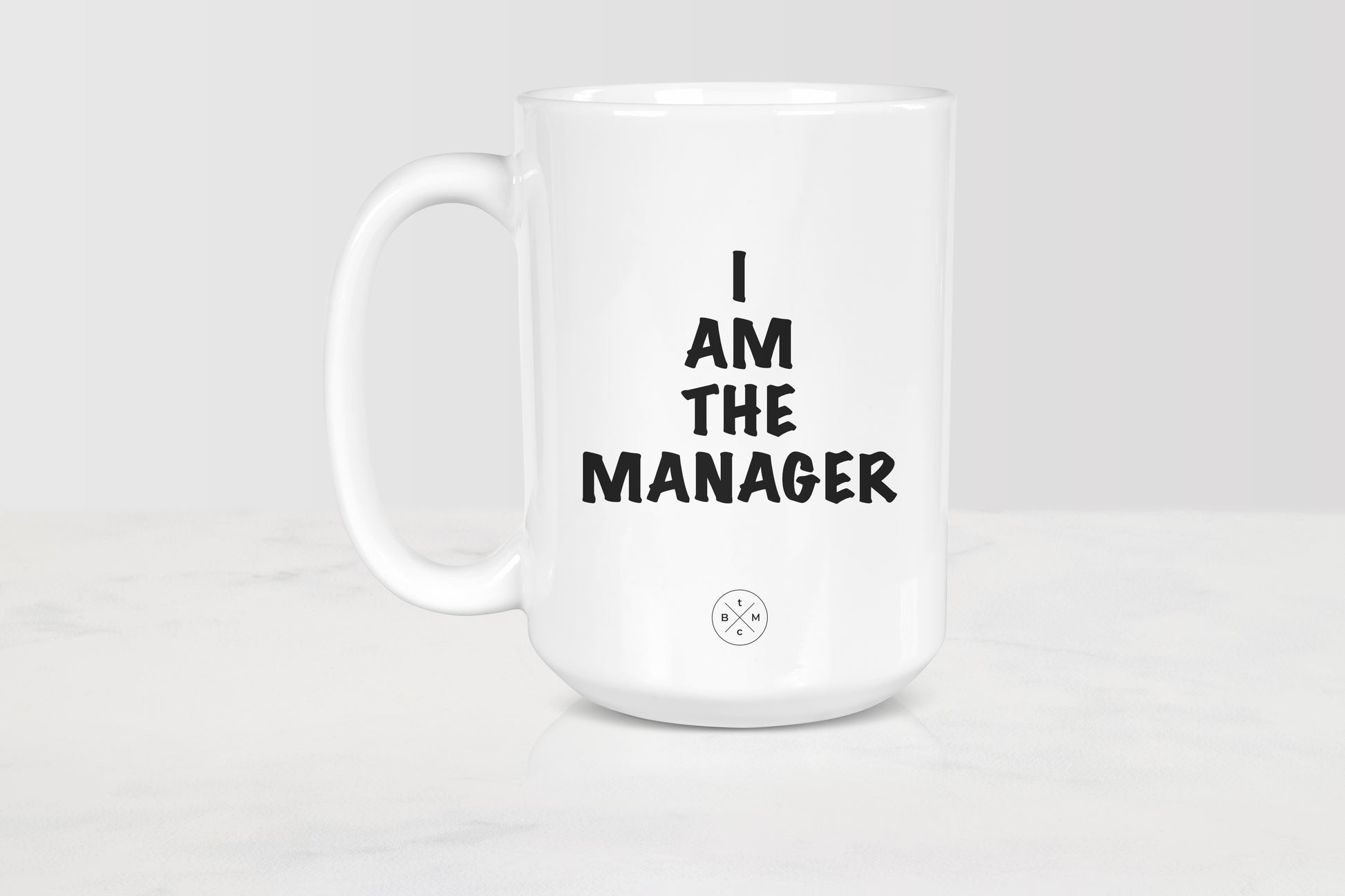 15 ounce white ceramic mug with black text I am the manager