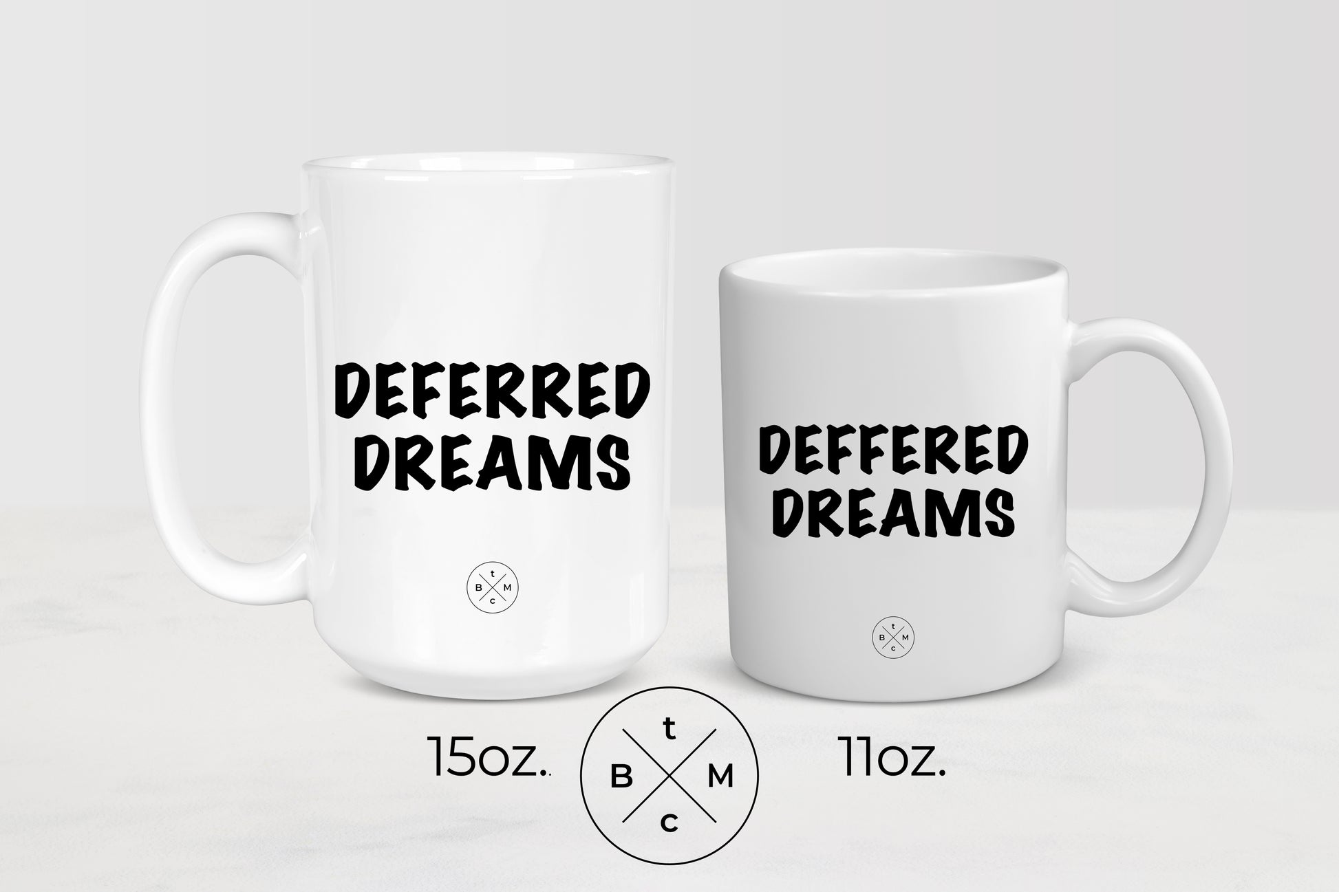 11 ounce and 15 ounce white ceramic mugs with black text deferred dreams