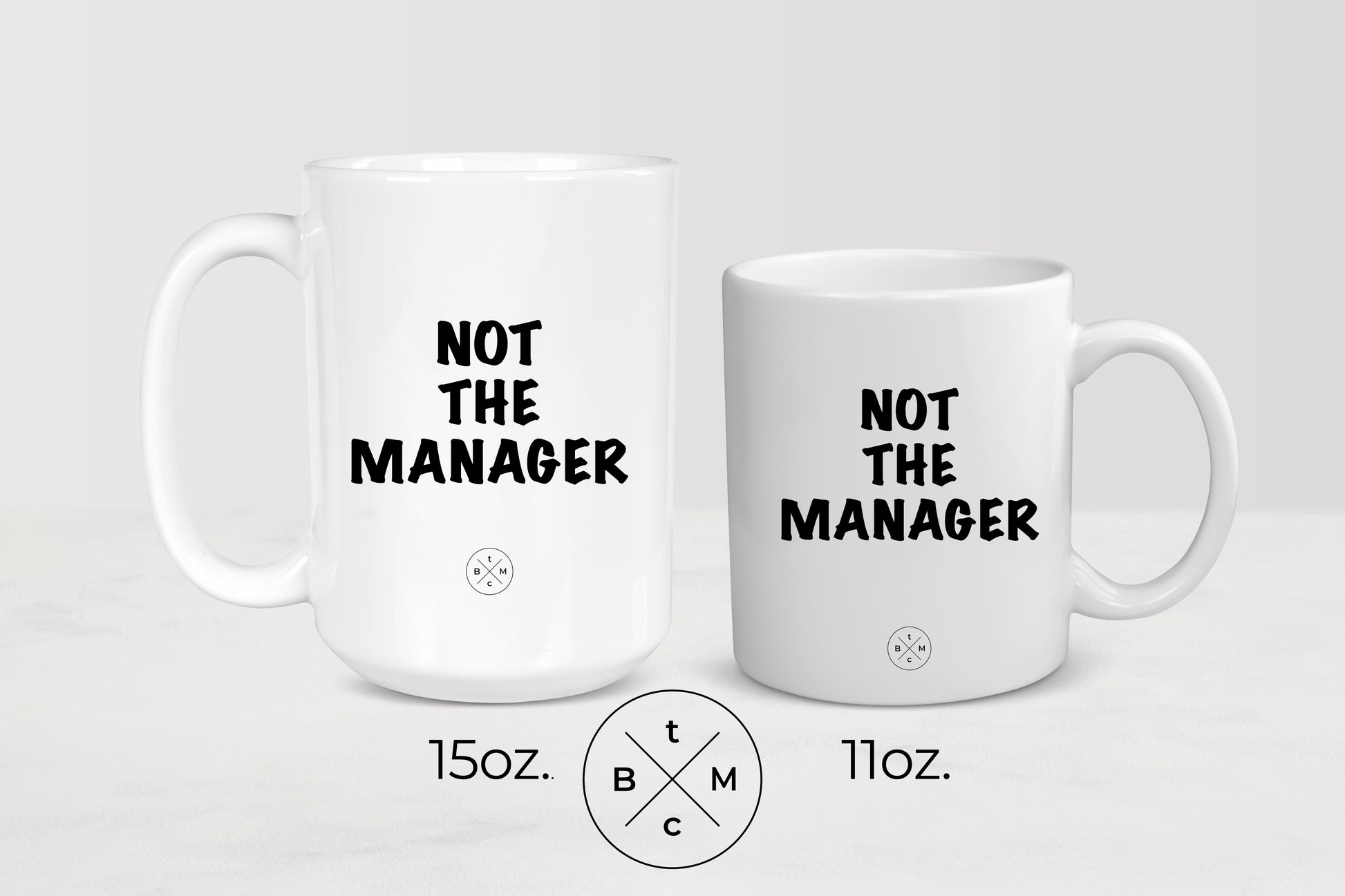 11 ounce and 15 ounce white ceramic mugs with black text not the manager
