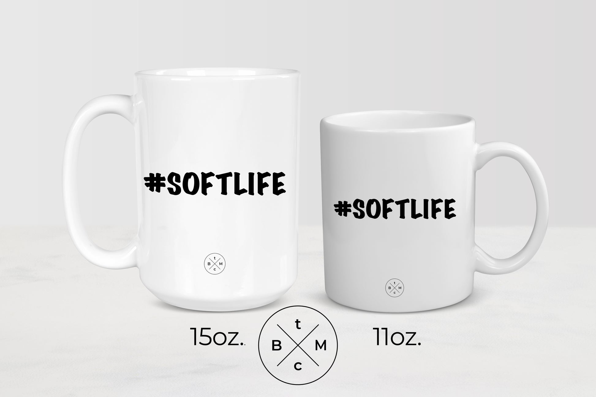 White 11 ounce and 15 ounce ceramic mugs with black text #SoftLife